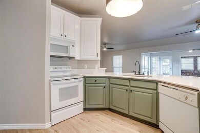Kitchen with sink, light wood-type flooring, white cabinetry, white appliances, and ceiling fan