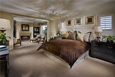 Master bedroom with decorative wall treatment with shutters and crown moulding, looking into master retreat with wood burning gas fireplace.