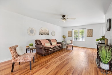 Living room with ceiling fan and light hardwood /