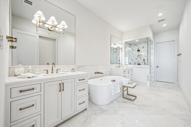 Polished marble makes the primary bathroom gleam. 24x24 tile flooring, large format brick design wainscoting, and herringbone shower accent wall keep the visual interest while tying together the look. The 67