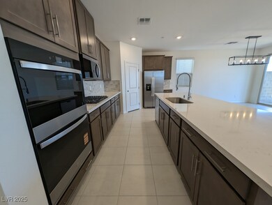 Kitchen featuring appliances with stainless steel finishes, dark brown cabinetry, light tile patterned floors, decorative backsplash, and recessed lighting
