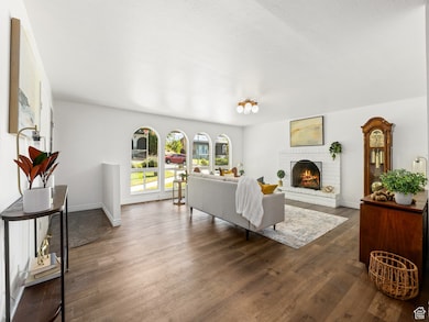 Living room with a brick fireplace and dark wood-style floors