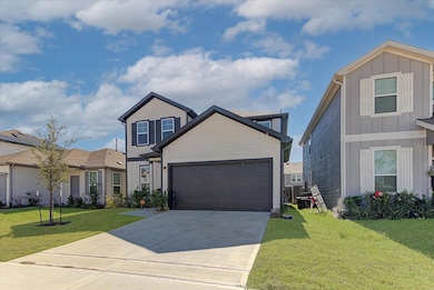 This is a modern two-story home with a clean exterior featuring a dark garage door and neutral siding. It has a spacious driveway, a small front yard with minimal landscaping, and is situated in a suburban neighborhood with similar-style houses.