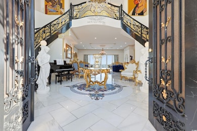 Foyer entrance with a chandelier, a high ceiling, marble finish floors, ornamental molding, and stairway