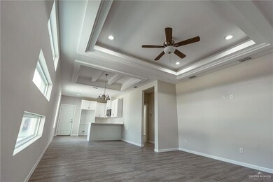 Unfurnished living room with a raised ceiling, ceiling fan, and light hardwood / wood-style flooring