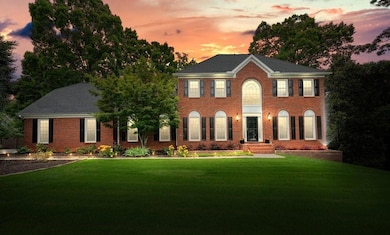Colonial home featuring a yard and brick siding