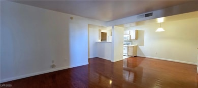 Unfurnished living room featuring wood finished floors and baseboards