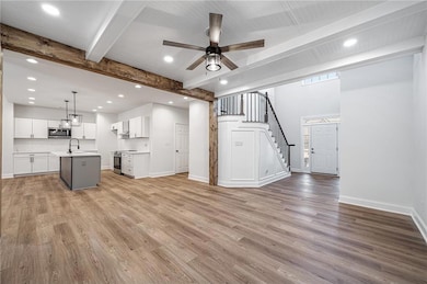 Unfurnished living room with beamed ceiling, a ceiling fan, recessed lighting, and a sink