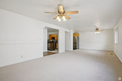 Carpeted spare room with a ceiling fan and baseboards