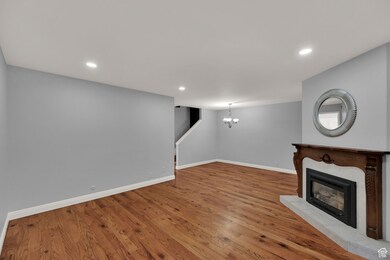 Unfurnished living room featuring a fireplace, recessed lighting, wood finished floors, and a chandelier