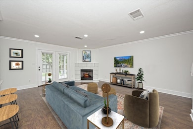 Living area with crown molding, visible vents, an