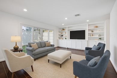 Virtually Staged. The living room is anchored by a wall of built-ins, offering a perfect spot for a TV, display for decorative items, and generous storage below. Sliding doors open to the patio, creating an easy flow for indoor–outdoor living.