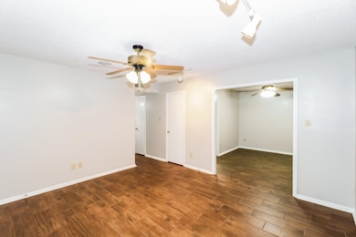 Spare room with a textured ceiling, dark wood finished floors, rail lighting, and a ceiling fan