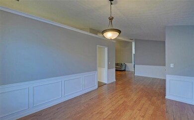 Empty room featuring wainscoting, wood finished floors, and a decorative wall