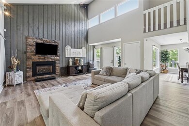 Living room featuring a high ceiling, wood finished floors, a fireplace, wood walls, and a chandelier