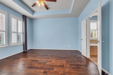 Primary Bedroom with hardwood flooring and tray ce