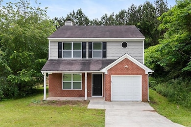 View of front of property with a front yard, brick siding, a chimney, and driveway
