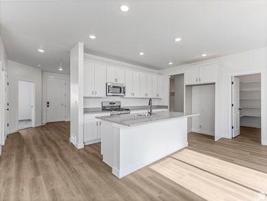 Kitchen with white cabinets, a kitchen island with sink, light wood-style flooring, stainless steel appliances, and recessed lighting