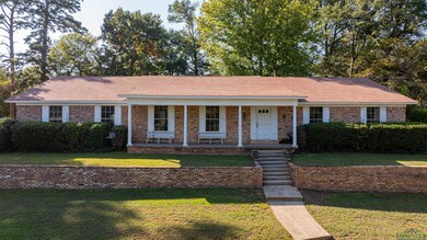 Ranch-style home featuring a front lawn and covere