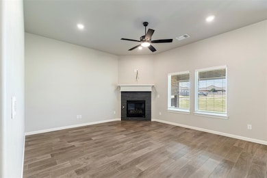 Unfurnished living room featuring a glass covered fireplace, light wood finished floors, a ceiling fan, and recessed lighting