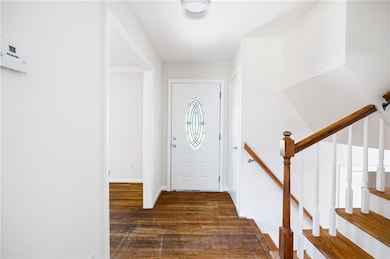 Foyer featuring dark wood-style floors and baseboards