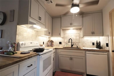 Kitchen featuring white appliances, a ceiling fan, under cabinet range hood, and gray cabinets