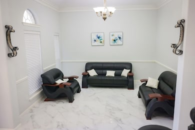 Living area featuring marble finish flooring, ornamental molding, and a chandelier