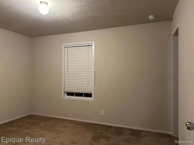 Empty room with a textured ceiling and carpet flooring