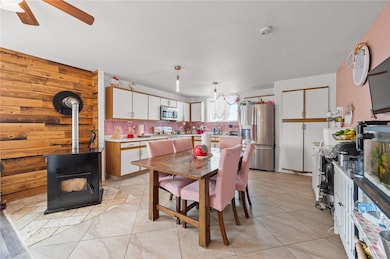 Dining area featuring a wood stove, light tile patterned floors, and wood walls