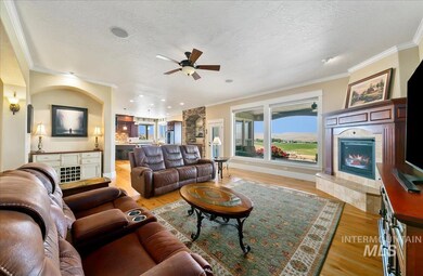 Living room featuring a tile fireplace, light wood-style floors, ceiling fan, crown molding, and a textured ceiling