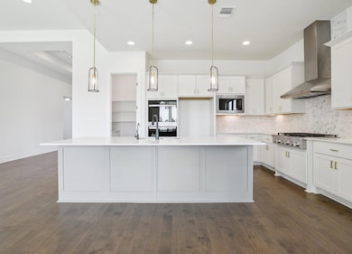 Kitchen with white cabinetry, wall chimney exhaus
