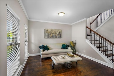 Living area featuring crown molding, dark wood finished floors, and stairway