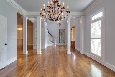 Unfurnished dining area featuring stairs, wood finished floors, ornamental molding, and ornate columns