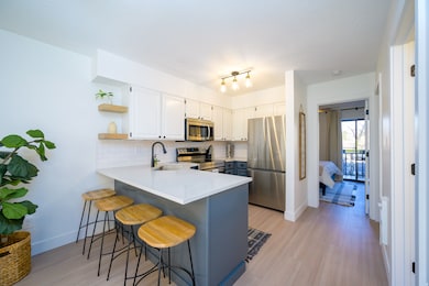Kitchen with open shelves, appliances with stainless steel finishes, a breakfast bar area, a peninsula, and decorative backsplash