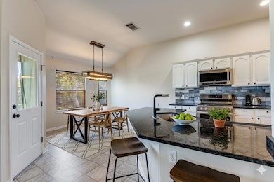 Kitchen featuring white cabinets, dark stone coun