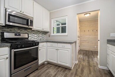 The Kitchen features White Cabinets that stretch to the ceiling, Stainless Steel Appliances, and Stone Countertops