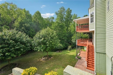 View of grassy yard featuring stairs and a balcony