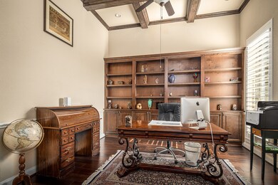A private study is accented with stained beams in the ceiling, built-in bookshelves and cabinets plus plantation shutters.