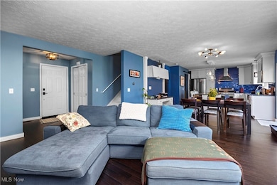 Living area with a chandelier, dark wood-style floors, and a textured ceiling