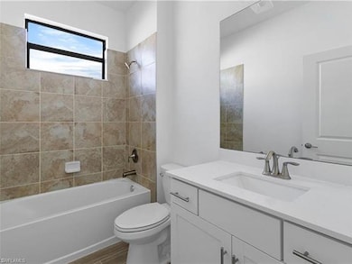 Full bath with tub / shower combination, toilet, wood finished floors, and vanity