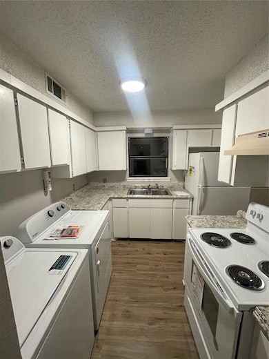 Kitchen with white range, white cabinetry, a textured ceiling, and stainless steel fridge