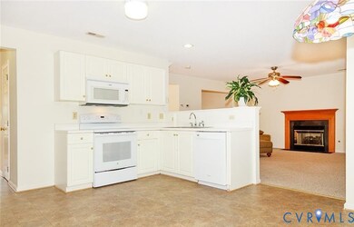 Kitchen with white appliances, a fireplace with flush hearth, light countertops, white cabinetry, and recessed lighting