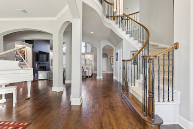 Foyer entrance with stairway, arched walkways, dark wood-style flooring, ornamental molding, and a high ceiling