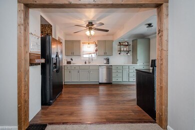 Kitchen with dark hardwood floors, stainless steel dishwasher, light countertops, ceiling fan, and black refrigerator with ice dispenser