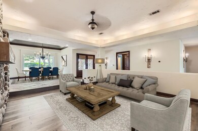 Living room featuring a tray ceiling, ceiling fan 