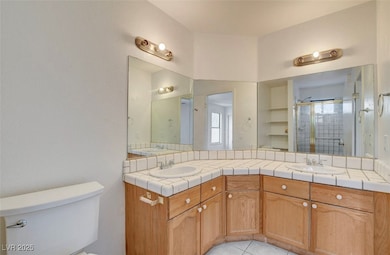 Full bath featuring double vanity, a shower stall, and light tile patterned floors