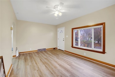 Unfurnished room featuring light wood finished floors, arched walkways, and a ceiling fan