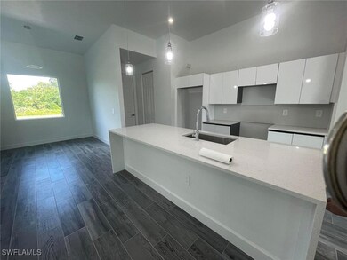 Kitchen featuring a sink, baseboards, white cabine