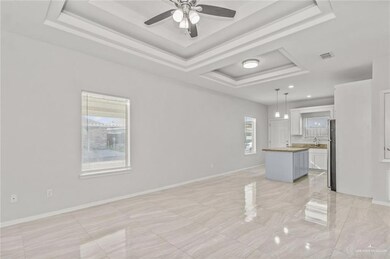 Unfurnished living room with a sink, a raised ceiling, a ceiling fan, baseboards, and visible vents