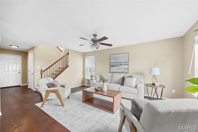 Living area with stairs, dark wood finished floors, and a ceiling fan